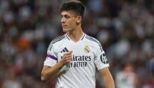 Real Madrid formasını giyen Arda Güler, stadyumda ellerini göğsünde tutarken maça odaklanmış görünüyor.