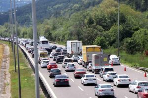 Ormanlık alandan geçen otoyolda yoğun araç trafiği, kamyonlar ve kamyonetler ters yönde ilerliyor.