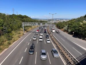 Kocaeli’de otoyolda yoğun araç trafiği, şehir manzarası ve ağaçlık alanlar arasında uzanan yol.