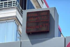 Diyarbakır yazılı LED dijital hava durumu panosu kırmızı ışıklarla açık, mavi gökyüzü altında.