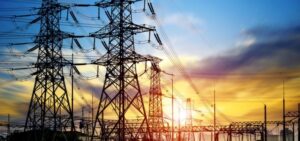 Alacakaranlıkta elektrik iletim hatları ve yüksek gerilim kuleleri görünüyor