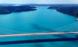İstanbul Boğazı üzerinde turkuaz sular ve çok kemerli köprü manzarası, çevrede ormanlık tepeler görülüyor.