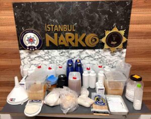 İstanbul NARCO pankartı önünde çeşitli şişeler, bidonlar, poşetler ve ölçüm kapları sergilenmiş.