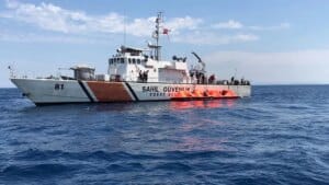 Sahil Güvenlik botu denizde, üzerinde 81 numarası ve turuncu kurtarma botu bulunan personel görülüyor.