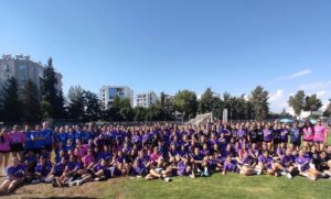 Mavi ve mor formalar giymiş, çim alanda toplanmış voleybolcuların grup fotoğrafı, Merve Çelebi Voleybol Akademi 5. yıl…