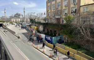 İnsanların yürüdüğü yol ve modern binaların yanında Bizans tarzı tarihi yapı ile cami minaresi görünüyor.