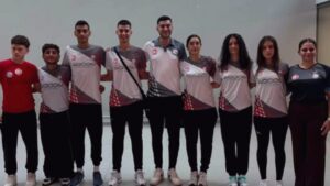 Badminton takım forması giymiş sporcular beyaz arka plan önünde ayakta yan yana fotoğraf çekiminde