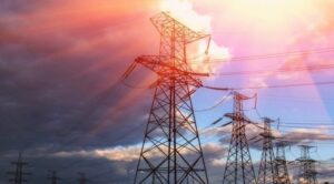 Gökyüzü altında yüksek gerilim elektrik direkleri ve iletim hatları.
